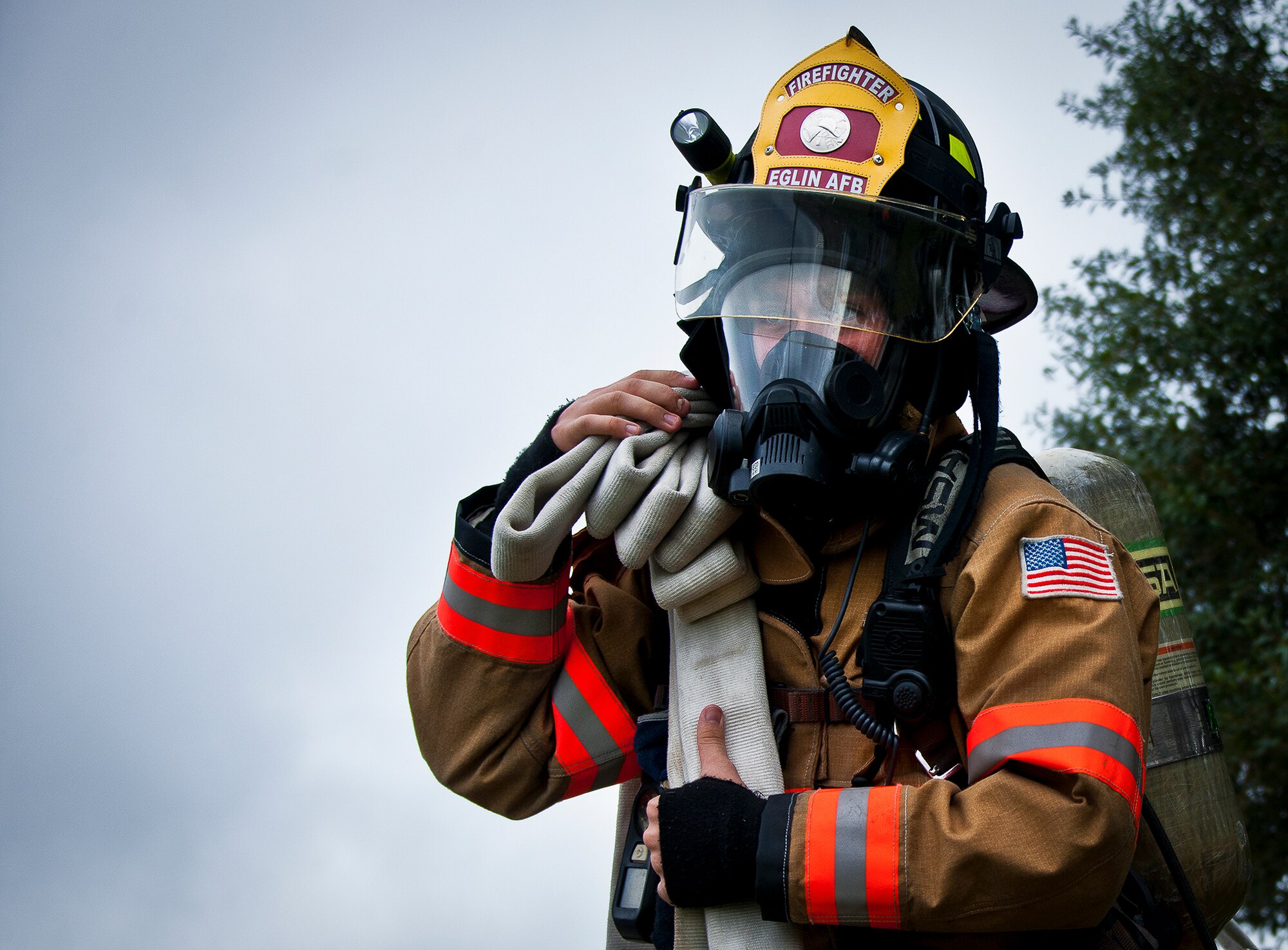 Senior Airman Paul Steele, of the 96th Civil Engineer Squadron, hauls out a water hose to douse the flames of a fire caused by a simulated explosion during a radiological and force protection condition exercise Aug. 16 at Eglin Air Force Base, Fla.  First responders from security forces, the fire department and medical group arrived to secure the scene and help the simulated victims.  (U.S. Air Force photo/Samuel King Jr.)