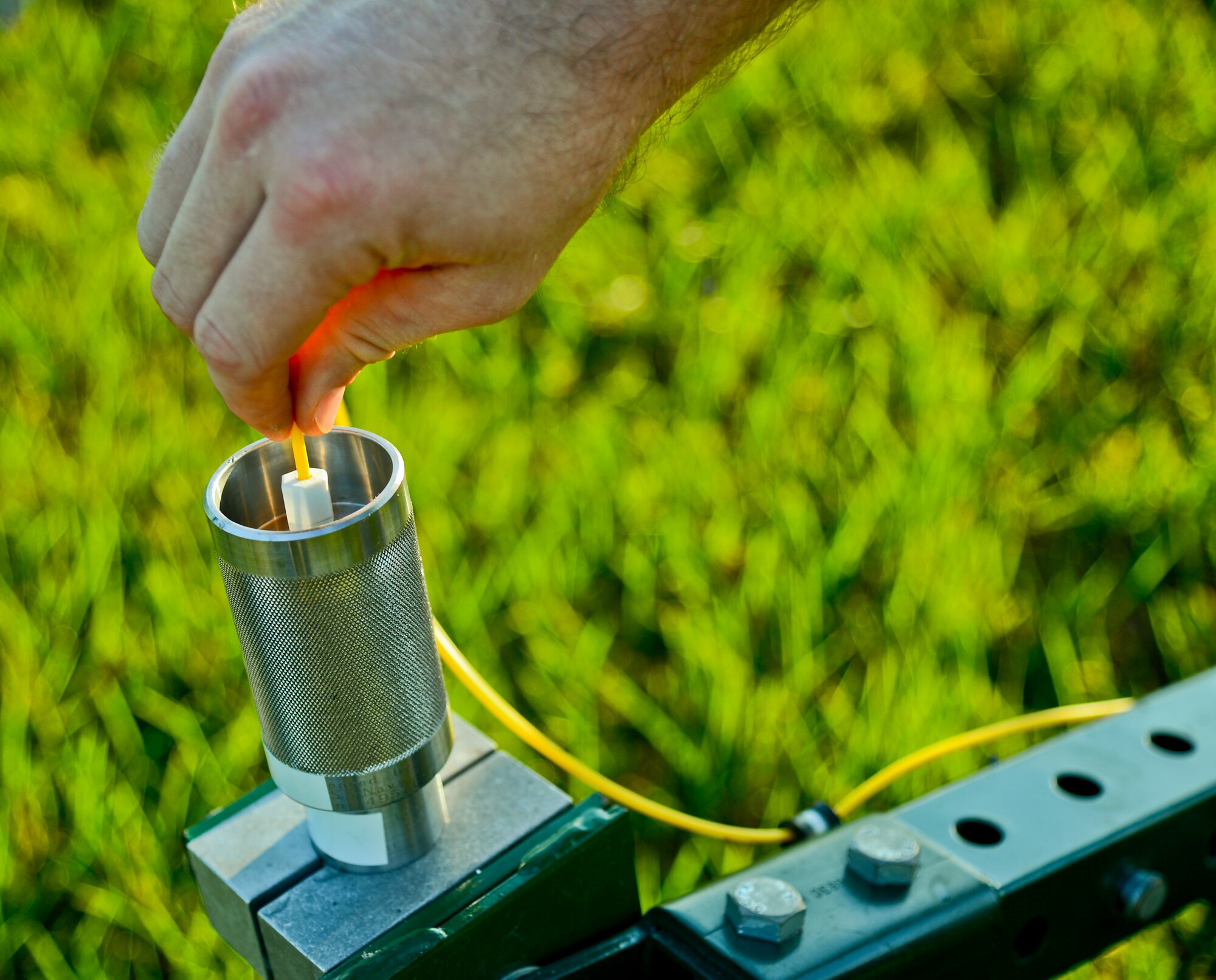 An explosive ordnance disposal technician with 6th Civil Engineer Squadron, threads shock tube, a hallow tube of explosives, into the end of a percussion actuated neutralizer (PAN) during a training scenario Aug. 15, 2013, at MacDill Air Force Base, Fla. Airmen from 6th CES demonstrated proper disposal techniques during a month-long training session on conventional munitions. . (U.S. Air Force photo by Airman 1st Class Ned T. Johnston/Released)