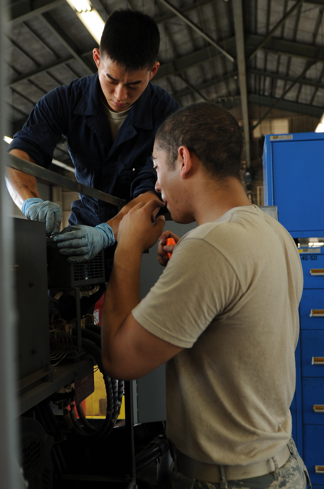 YOKOTA AIR BASE, Japan -- Left, Airman 1st Class Justin Yi and Eric Stewart, both of the 374th Maintenance Squadron, put together a generator during an inspection Aug. 14, 2013, at Yokota Air Base, Japan. The Aerospace Ground Equipment flight conducts bi-annual inspections and maintenance on equipment used on the flightline. (U.S. Air Force photo by Senior Airman Desiree Economides)
