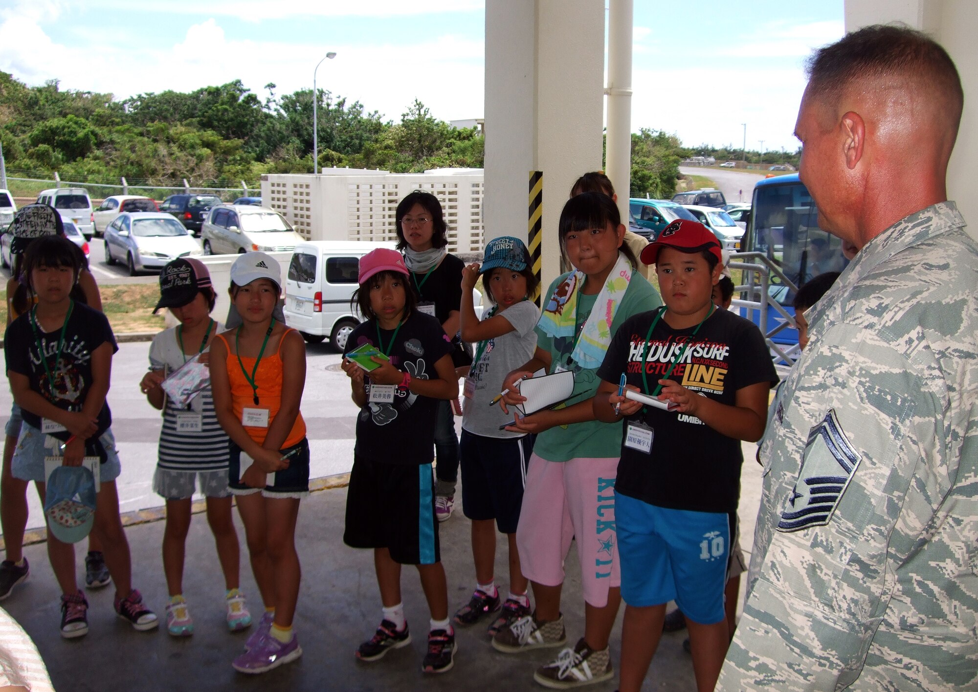 Japanese primary school children from Nagano Achi village take notes during a brief by U.S. Air Force Senior Master Sgt. Bruce Gegner, 733rd Air Mobility Squadron air terminal superintendent, on Kadena Air Base, Japan, Aug. 5, 2013. This visit allowed the students to learn about the culture and experience military activities. (Courtesy photo)
