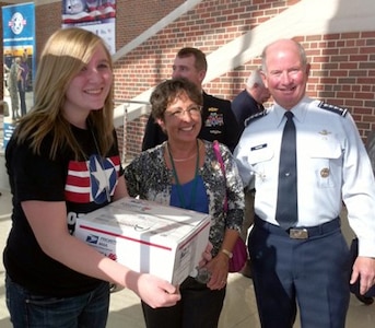 Air Force Gen. Duncan J. McNabb, Commander, U.S. Transportation Command, Scott Air Force Base, Ill and his wife are assisted by Emily Hulberg, Missouri National Guard's Teen Leadership Council, in preparing their package for Operation Homefront.