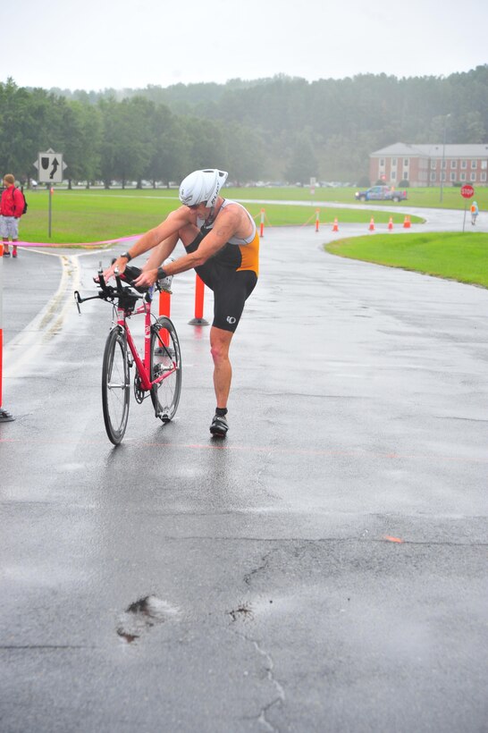Triathlete, Douglas Dudgeon, dismounts his bicycle during a triathlon hosted by the Marine Corps Marathon aboard Marine Corps Marathon on Aug. 18, 2013. The event was the first triathlon hosted by the Marathon.