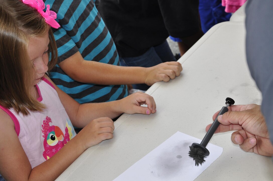 Bella, 6, watches a fingerprint dusting demonstration at the 2013 National Day Out: Back to School Event on Aug. 18, 2013, outside of the Lincoln Military Housing Family Housing Center aboard Marine Corps Base Quantico. The Provost Marshal's Office, Marine Corps Community Services and Lincoln Military Housing co-sponsored the event after National Night Out was cancelled on the base due to budget cuts.