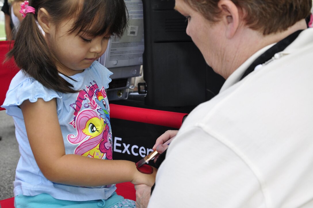 Ayanna, 4, gets a ladybug painted on her hand at the facepainting booth during 2013 National Day Out: Back to School Event on Aug. 18, 2013, outside of the Lincoln Military Housing Family Housing Center aboard Marine Corps Base Quantico. The Provost Marshal's Office, Marine Corps Community Services and Lincoln Military Housing co-sponsored the event after National Night Out was cancelled on the base due to budget cuts.