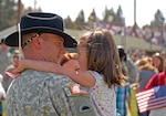 A soldier with 1st Squadron, 82nd Cavalry, 41st Infantry Brigade Combat Team of the Oregon National Guard, holds his daughter before a demobilization ceremony following a year-long absence to Iraq in support of Operation Iraqi Freedom at Vince Genna Stadium in Bend, Ore., April 18, 2010.