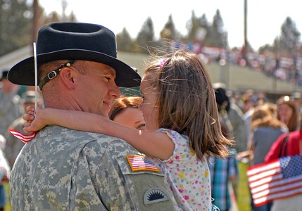 A soldier with 1st Squadron, 82nd Cavalry, 41st Infantry Brigade Combat Team of the Oregon National Guard, holds his daughter before a demobilization ceremony following a year-long absence to Iraq in support of Operation Iraqi Freedom at Vince Genna Stadium in Bend, Ore., April 18, 2010.