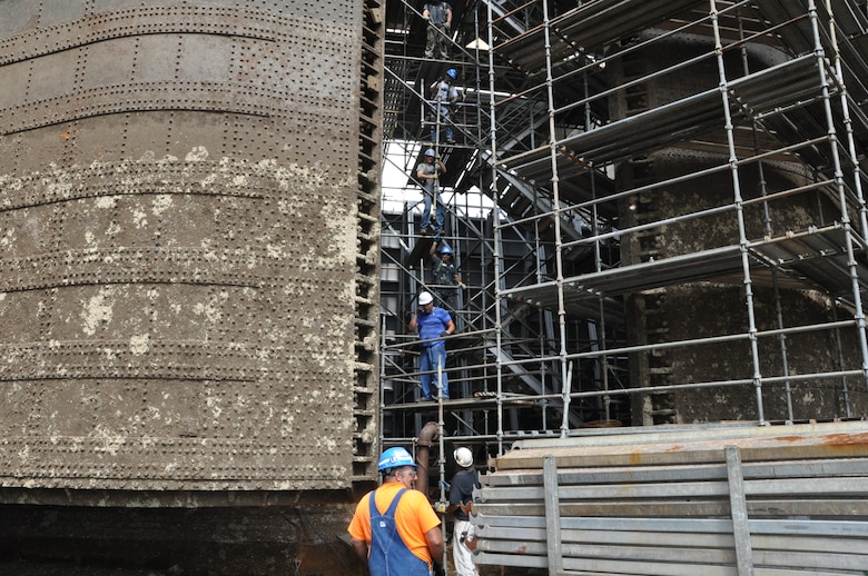 Seven workers pass scaffolding sections up the chamber side of Kentucky Lock’s lower miter gate Aug. 19, 2013. The wraparound scaffold is being assembled to permit TVA-contracted GUBMK Constructors to sandblast, make any needed internal structural repairs, and paint the 91-foot tall miter gates. The U.S. Army Corps of Engineers Nashville District employees dewatered the 69-year-old, 110-by-600-foot lock and will inspect the culvert valves and all other areas of the lock that are normally underwater for any needed repairs. Corps employees will also replace the tow haulage system, used to move unpowered sections of barge tows through the lock. Kentucky lock is scheduled to resume normal operation at noon, Sept. 24, 2013.