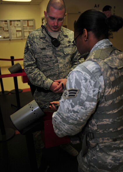 Staff Sgt. Craig Sams ensures Senior Airman Mikeya Crowley is properly arming before assuming her post at Fairchild Air Force Base, Wash., Aug. 8, 2013. Sams and Crowley are both installation patrolmen with the 92nd Security Forces Squadron. (U.S. Air Force photo by Senior Airman Taylor Curry/Released) 