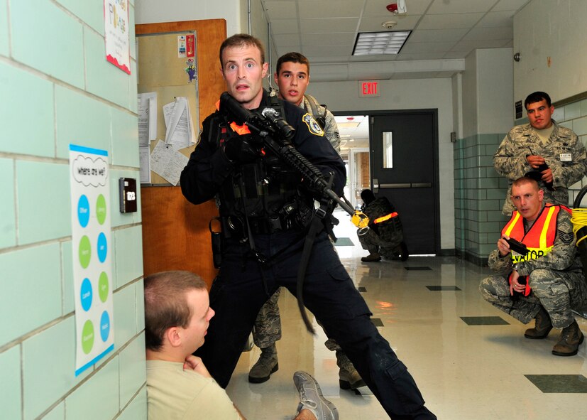 Justin Viens, front, and Senior Airman Guerreros Reynoso, both of the 436th Security Forces Squadron, look down a hallway for an active shooter Aug. 13, 2013, at Major George S. Welch Elementary School on Dover Air Force Base, Del. Viens and Reynoso were part of a response team that responded to a scenario at the school during the major accident response exercise. (U.S. Air Force photo/Tech. Sgt. Chuck Walker)