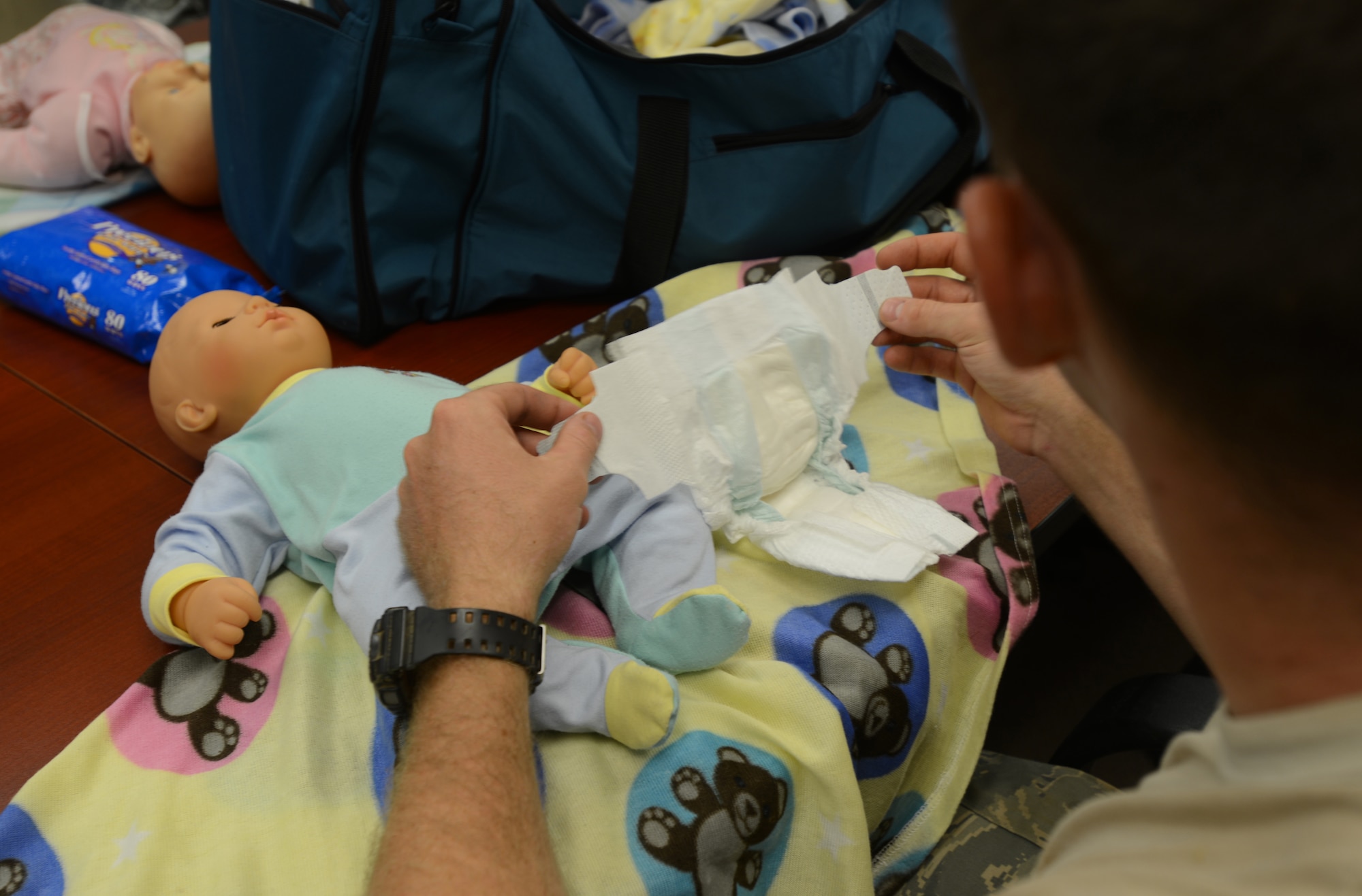 A U.S. Air Force Airman practices changing a diaper during a Dads 101 class at Shaw Air Force Base, S.C., July 17, 2013. The class is designed to educate new dads on topics such as caring and bonding with a newborn baby, normal crying cycles of infants, how to cope with inconsolable crying, stages of normal bonding/attachment, (and specifically for military members) deployments and parenting. (U.S. Air Force photo by Airman 1st Class Jensen Stidham/Released)