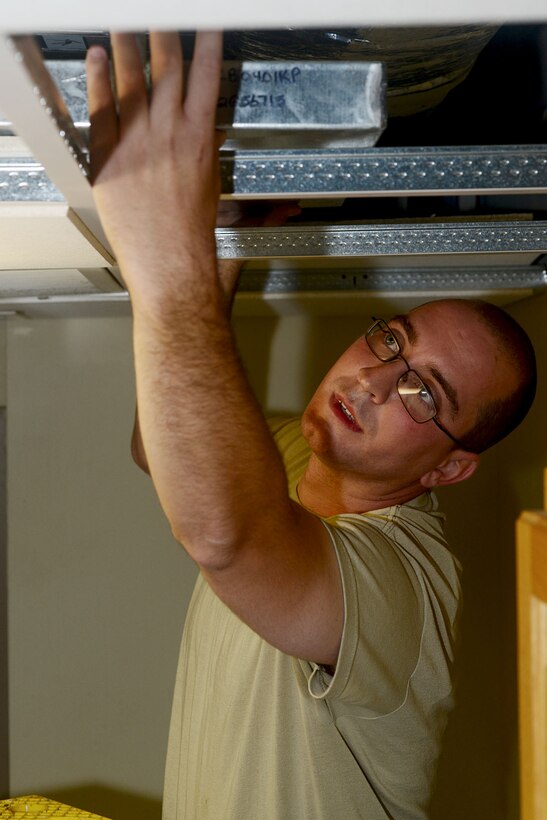 U.S. Air Force Staff Sgt. Andrew LaBrake, 633rd Civil Engineer Squadron heating, ventilation and air conditioning craftsman, replaces the condensation pan after repairing an air conditioner fan coil unit at Langley Air Force Base, Va., Aug. 16, 2013. The pan is used to control condensation from the fan coil that controls the temperature set by the thermostat. (U.S. Air Force photo by Staff Sgt. Ashley Hawkins/Released)