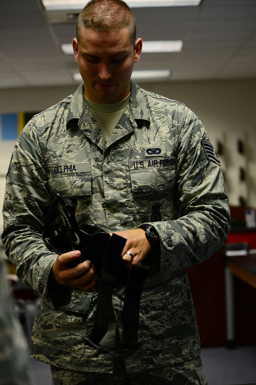 U.S. Air Force Staff Sgt. William Delphia, 633rd Security Forces Squadron combat arms training and maintenance instructor, inspects an M9 Beretta pistol holster before the firing portion of class at Langley Air Force Base, Va., Aug. 13, 2013. The CATM classes are broken down into an instruction portion and a firing portion. (U.S. Air Force photo by Staff Sgt. Ashley Hawkins/Released)