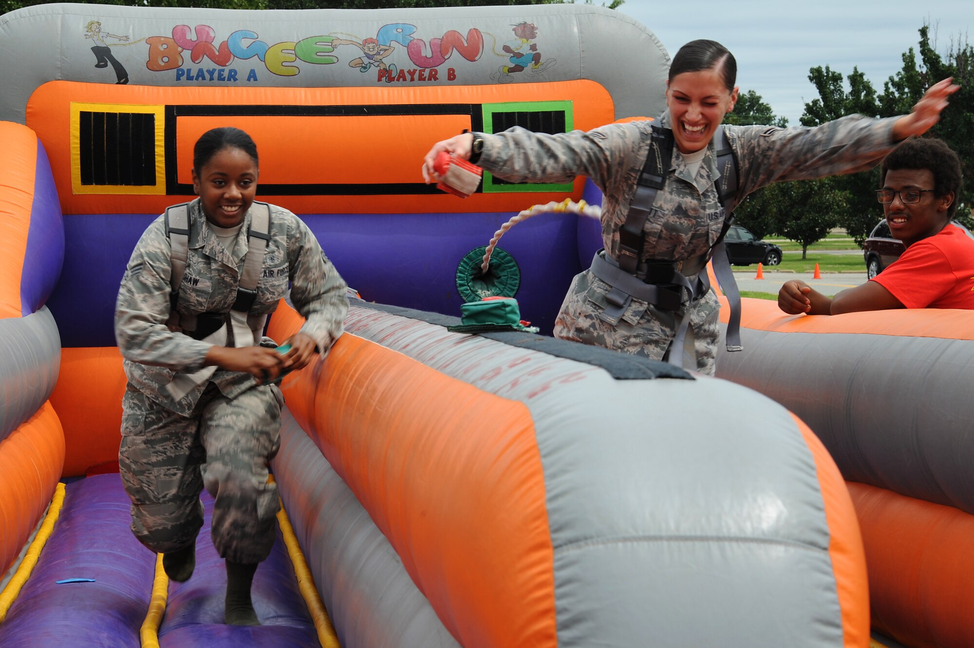 From right, U.S. Air Force Senior Airman Alexis Shaw, 633rd Force Support Squadron services journeyman, and Airman 1st Class Michelle Garrett from the 633rd Civil Engineer Squadron, compete in a “bungee run” during the “We Are Family” campaign reunion at Langley Air Force Base, Va., Aug. 16, 2013. The reunion also offered an outdoor cookout, information booths, multiple contests and a perfomance by the Air Force band, the Blue Aces. (U.S. Air Force photo by Airman 1st Class Victoria H.Taylor/Released)