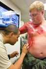 Airman 1st Class Alan Mejia, left, 436th Aerospace Medicine Squadron public health technician, applies moulage to Senior Airman Colby Wentland, a loadmaster with the 9th Airlift Squadron August 13, 2013, at Dover Air Force Base, Del. Mejia helped moulage Wentland and 19 other role players prior to a simulated chemical spill at the main gate during the second day of a major accident response exercise. (U.S. Air Force photo/Roland Balik)
