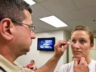 Terry Kauffman, left, a safety and security constable with Bayhealth Medical Center, Dover, Del., applies moulage to Staff Sgt. Carol Mitchell, 436th Aerospace Medicine Squadron, noncommissioned officer in charge of Public Health August 13, 2013, at Dover Air Force Base, Del. Over the years, Kauffman has volunteered his time applying moulage to role players during previous exercises. (U.S. Air Force photo/Roland Balik)