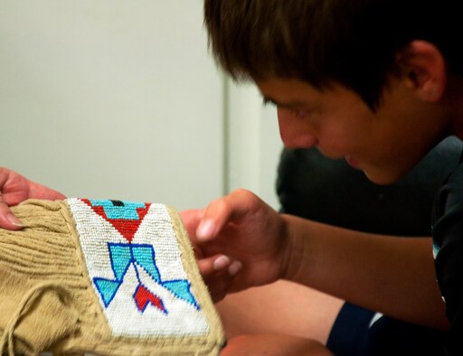 130813-F-GZ967-012 Joel Goatkin examines a real Shoshone quiver made from deerskin and beads that was brought in from the Wyoming State Museum in Cheyenne, Wyo. Goatkin was part of a Child and Youth Center and Arts and Crafts Center youth camp that explored the history of Wyoming. (U.S. Air Force photo by Airman 1st Class Brandon Valle)