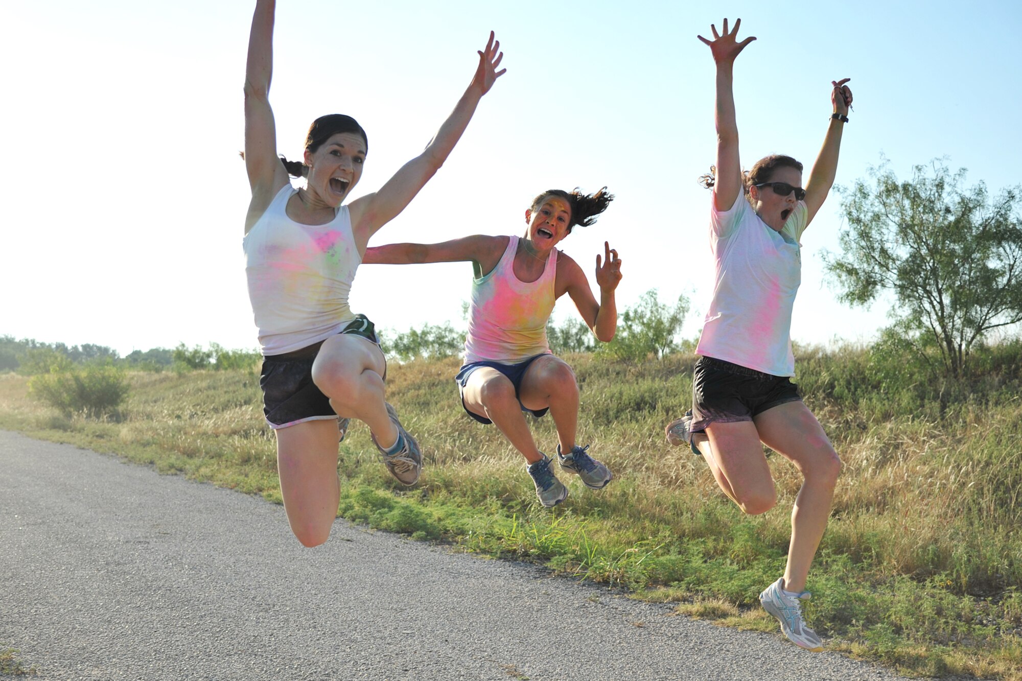 GOODFELLOW AIR FORCE BASE, Texas-- 1st Lt. Stephanie Martin, 2nd Lt. Eryn Avjian, and 1st Lt. Maggie Goff, 315th Training Squadron students, jump to pose for a photo during the Sexual Assault Prevention and Response Color Race on Kiowa Trail Aug 17. More than 100 participants came to show support by running the 5k. (U.S. Air Force photo/ Senior Airman Michael Smith) 