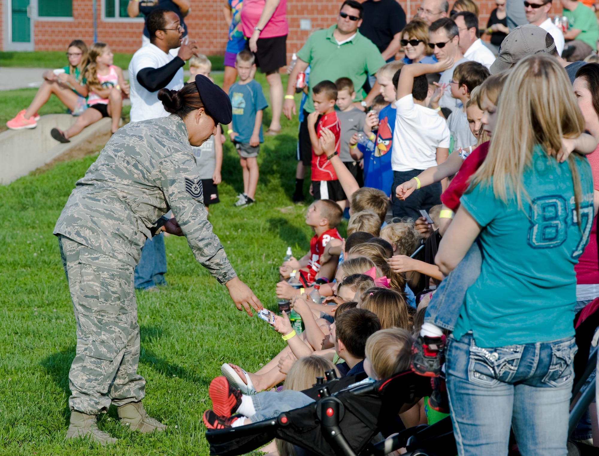 Tech. Sgt. Tanya Martinez, 22nd Security Forces Squadron kennel master, passes out dog cards to children at the first Back to School Blast event Aug. 17, 2013, at Park Hill Elementary School, Derby, Kan. The demonstration was provided to give the community a first-hand look at the abilities of MWDs. (U.S. Air Force photo/Airman 1st Class John Linzmeier)