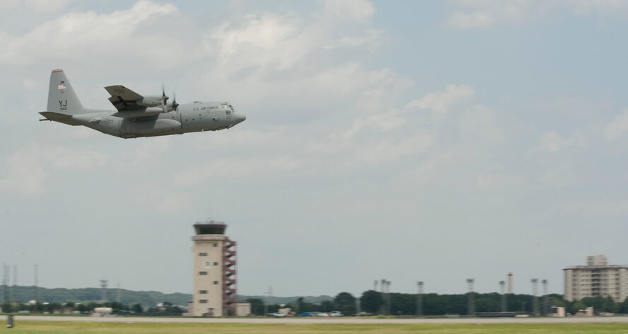 A C-130 Hercules soars past the control tower during a large formation mission at Yokota Air Base, Japan, Aug. 19, 2013. A total of seven C-130s took off to participate in the formation. (U.S. Air Force photo by Senior Airman Michael Washburn)