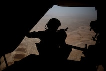 A gunner peers out the back of an MV-22B Osprey during a flight to Camp Dwyer, Afghanistan, Aug. 11, 2013. Maj. Gen. Walter Miller, commanding general Regional Command (Southwest), visited Camp Dwyer during a battlefield circulation to speak with servicemembers operating at the base. 