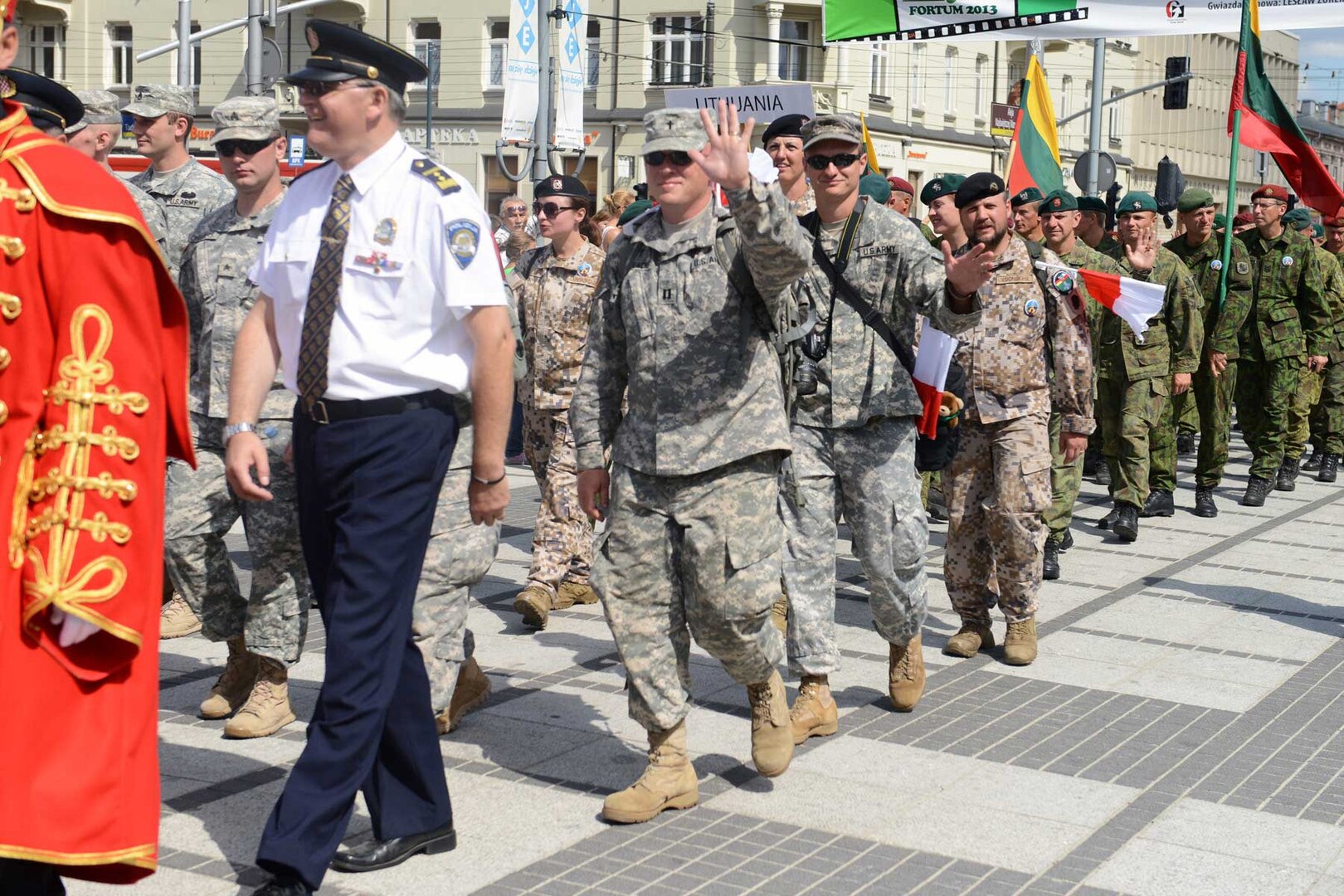 Illinois National Guard Chaplain J. Kroencke and Sgt. Ryan Twist wave to Polish people along the pilgrimage route in Czestochowa, Aug. 14, 2013.