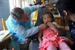 Lt. Col Jim Arneson, a dentist with the Alaskan Army National Guard, looks to see where the tooth hurts in the mouth of a young Mongolian girl with the help of translator, Ms. Oyun Erdone while at the Buynt Uhaa Complex in Ulaanbaatar, Mongolia Khaan Quest 2011. Khaan Quest 2013 is now under way.