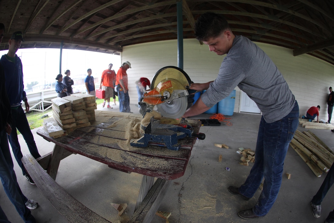 Lance Cpl. William Farrell, an infantryman with 2nd Battalion, 8th Marine Regiment, 2nd Marine Division, cuts wood to replace picnic tables and benches for Dixon Middle School in Holly Ridge, N.C., Aug. 15. The Marines have volunteered more than 72 hours of their own time this year.  
