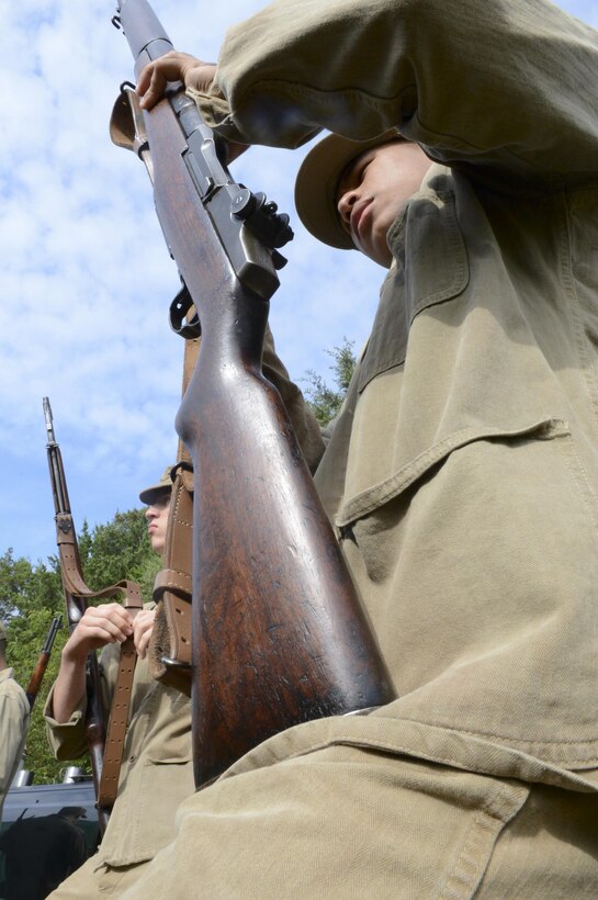 Marines prepare for their tactical demonstration while an M4 Sherman tank follows at the Virginia Museum of Military Vehicles on Aug. 17, 2013. The volunteers, wearing World War II-era Marine uniforms, engaged a fixed position with period weapons including an M2 flamethrower.