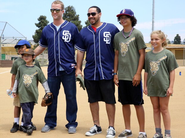 Children of depot personnel improve their batting, fielding and throwing skills during a baseball camp aboard Marine Corps Recruit Depot San Diego, Aug. 20. Members of the San Diego Padres baseball team, pitcher Brad Boxberger (left) and catcher Rene Rivera (right), took photos and autographed T-shirt after a Q and A session with the kids.
