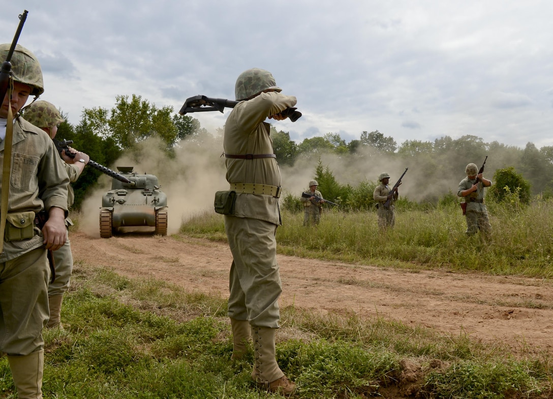 Marines prepare for their tactical demonstration while a M4 Sherman tank follows in tow at the Virginia Museum of Military Vehicles on Aug. 17. The volunteers donned World War II era Marine uniforms and weapons and engaged a fixed position with period weapons including an M2 flamethrower.