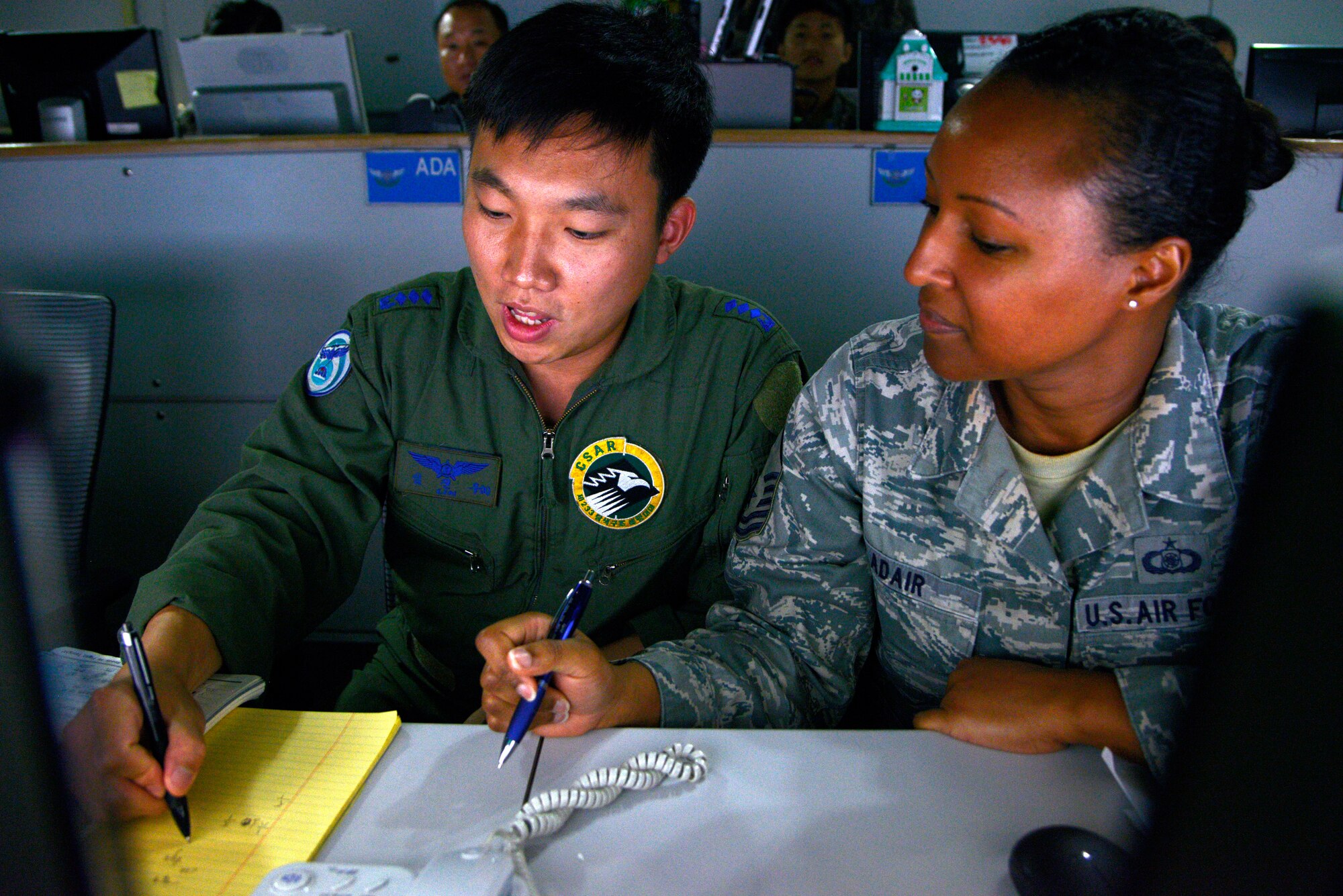 Republic of Korea Air Force Capt. Lim Jin Wuo, 6th Search and Rescue Group, shows U.S. Air Force Master Sgt. Kristian Adair, Joint Personnel Recovery Center member, how to write in Hangul, the native alphabet of the Korean language, in the Air Operations Center at Osan Air Base, ROK, Aug. 21, 2013, during Exercise Ulchi Freedom Guardian 2013. (U.S. Air Force photo/Staff Sgt. Sheila deVera)
