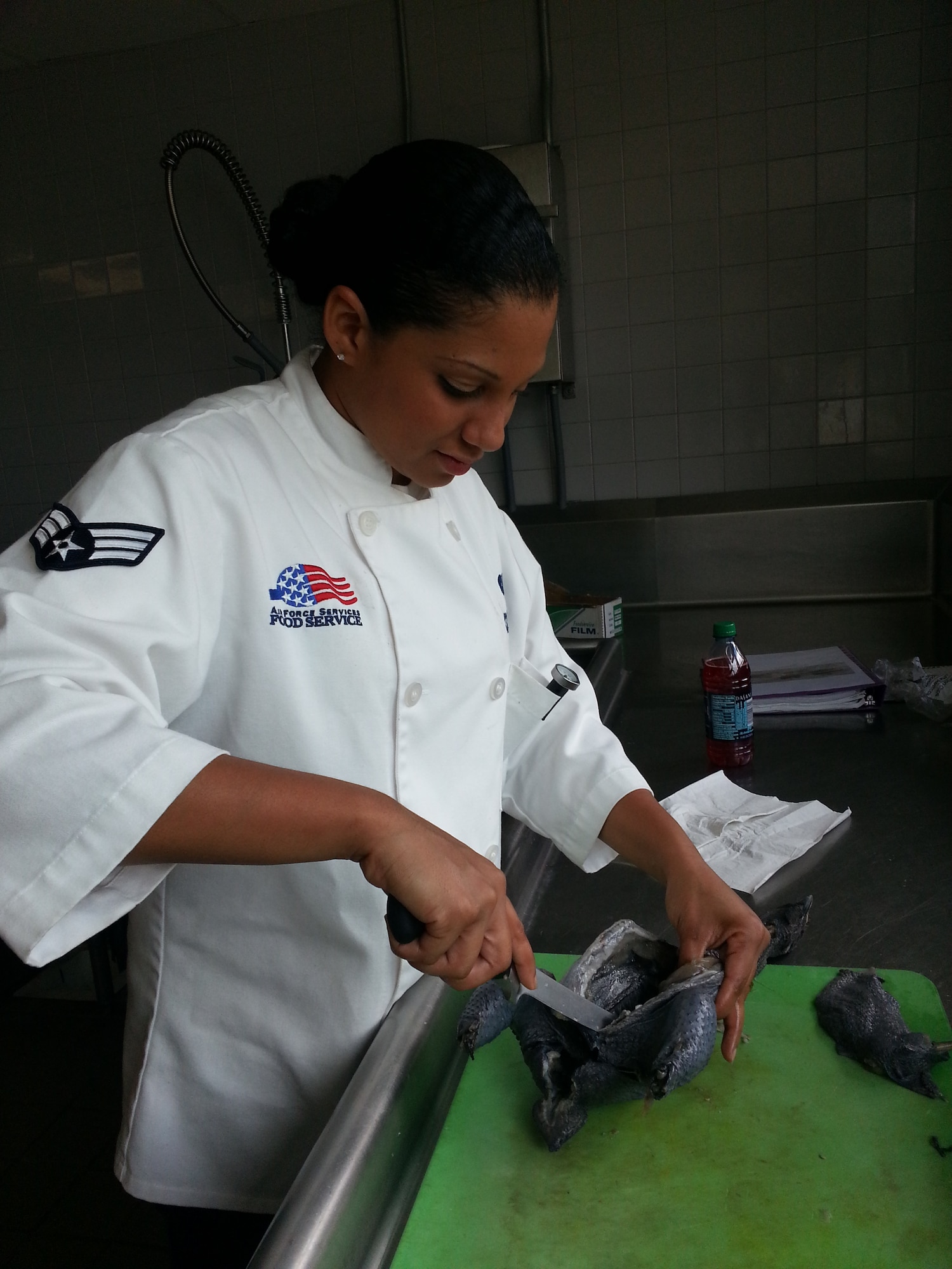 Senior Airman Carmen Gonzalez, 647th Force Support Squadron food service, cuts open a chicken while training for the U.S. Army’s 38th Annual Culinary Arts competition in Fort Lee, Va. Gonzalez  earned a gold medal for her hot dish of stuffed chicken with goat cheese and spinach, fluted mushrooms, turnee potatoes with balsamic vinegar  She was also awarded a silver medal in the cold food category and third place for the team category. (Courtesy photo)