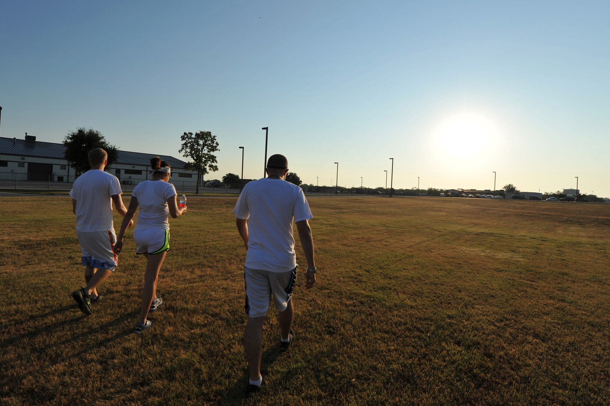 GOODFELLOW AIR FORCE BASE, Texas-- Airman 1st Class Jared Lunstad, 17th Civil Engineering Squadron, Airman 1st Class Victoria Gutierrez, 17th Medical Group, and Airman 1st Class Joshua Edwards, 17th Training Wing Public Affairs, walk towards the starting point of the Sexual Assault Prevention and Response Color Race on Kiowa Trail Aug. 17. More than 100 participants came to show support for SAPR by running the 5k. (U.S. Air Force photo/Senior Airman Michael Smith)