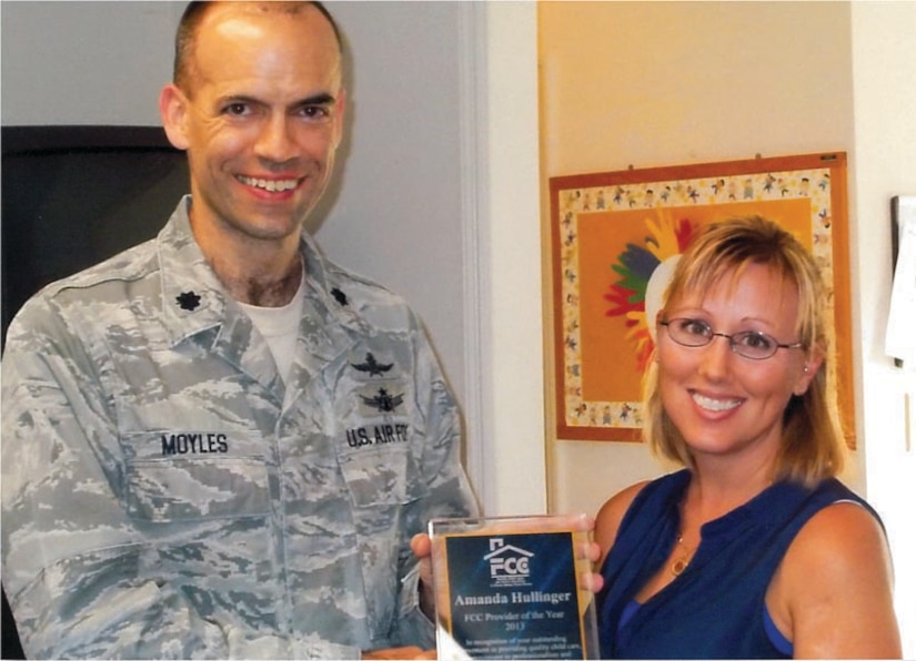 Amanda Hullinger, wife of Tech. Sgt. John Hullinger, 437th Aircraft Maintenance Squadron, was recently named the 2013 Family Child Care Provider of the Year for Joint Base Charleston.  Presenting Hullinger with her award is Lt. Col. Michael Moyles, 628th Mission Support Group deputy commander. A certified provider for more than two years, Hullinger currently cares for several children ages 7 months through early school age at her private residence through the Air Force Family Child Care Program. For information about FCC on base, call Sherian Vickers, JB Charleston FCC coordinator at 963-2547. (U.S. Air Force photo/Sherian Vickers)
