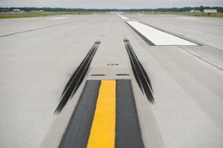 The first skid marks from a touch-and-go are emprinted on the pavement of the newly opened runway from a C-17 Globemaster III flown by Col. Darren Hartford, 437th Airlift Wing commander, and Col. James Fontanella, 315th Airlift Wing commander, performs a touch-and-go Aug.16, 2013 on the newly opened runway at Joint Base Charleston - Air Base, S.C. The newly constructed runway is 9,000 feet long and 150-feet wide and 18-inches thick at a cost approximately $40 million.The new runway will be capable  of supporting Air Force mission requirements and also serve teh local community. In addition, the project added high efficiency LED lighting fixtures, improved infrastructure for naviational aids and an an updated aircraft arresting system used to safely recover fighter aircraft experiencing mechanical issues. (U.S. Air Force photo/Tech. Sgt. Douglas)