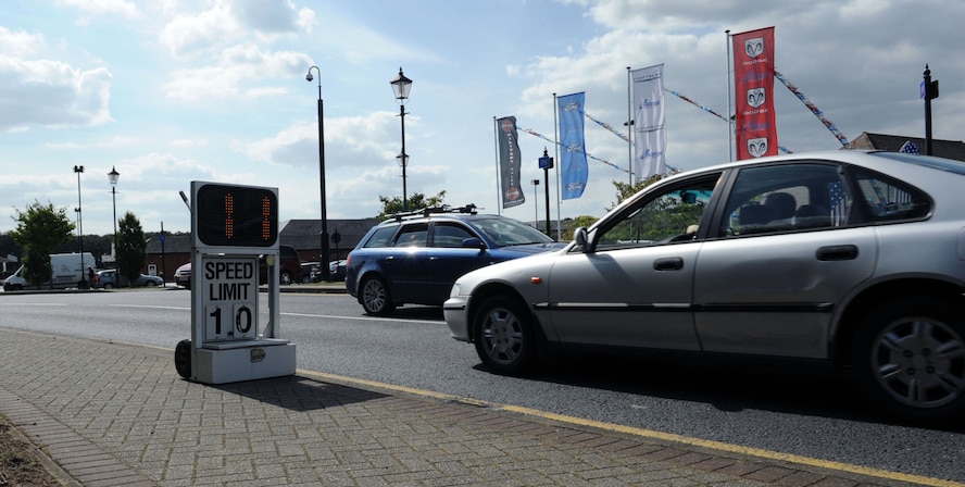 Cars drive through an area between housing and the school bus pick up/drop off point Aug. 21, 2013, on RAF Mildenhall, England. Motorists are reminded to obey posted speed limits and traffic laws, especially with school resuming Aug. 26. Pedestrians should cross streets at designated crosswalks and always look both ways for oncoming traffic. (U.S. Air Force photo by Airman 1st Class Preston D. Webb/Released)