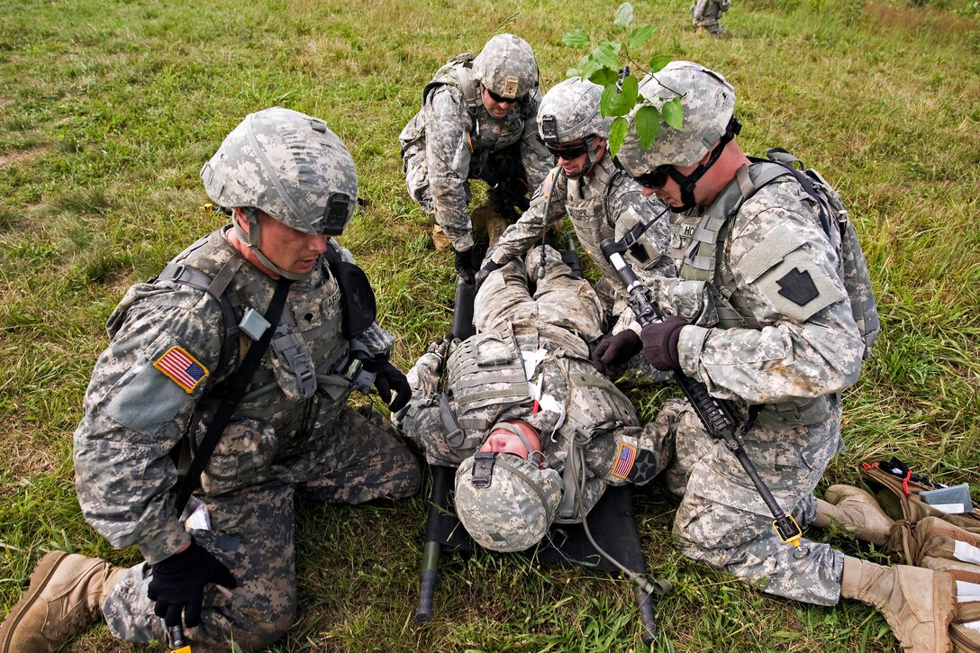 Soldiers provide tactical aid to a simulated wounded soldier during the squad battle course on Camp Atterbury, Ind., Aug. 12, 2013.