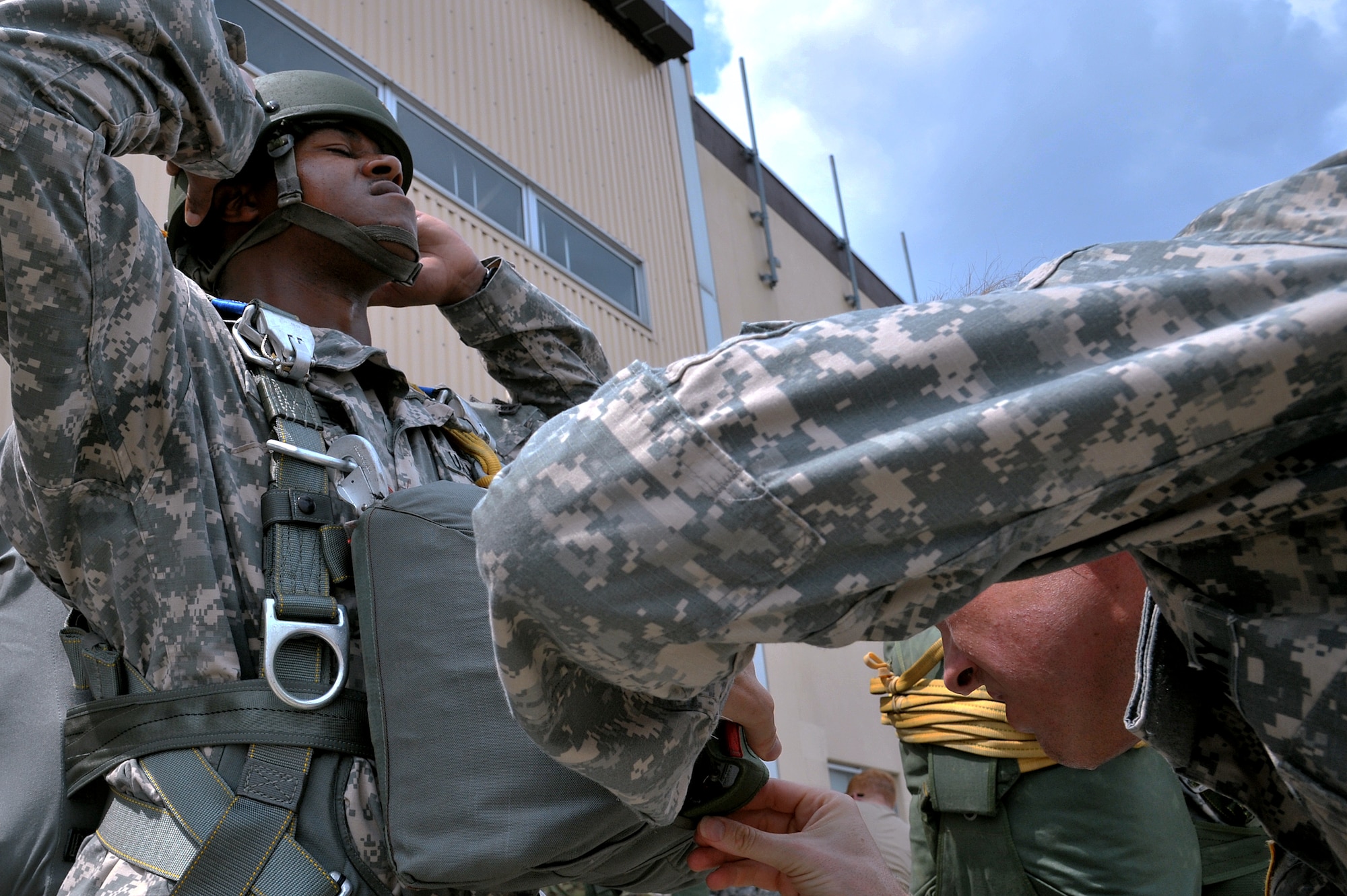 A Soldier helps a fellow paratrooper prepare his parachute rig before a training sortie at Yokota Air Base, Japan, Aug. 21, 2013.  U.S. Army paratroopers came to Yokota for joint jump training, benefiting both services’ interoperability.  (U.S. Air Force photo by Airman 1st Class Soo C. Kim)