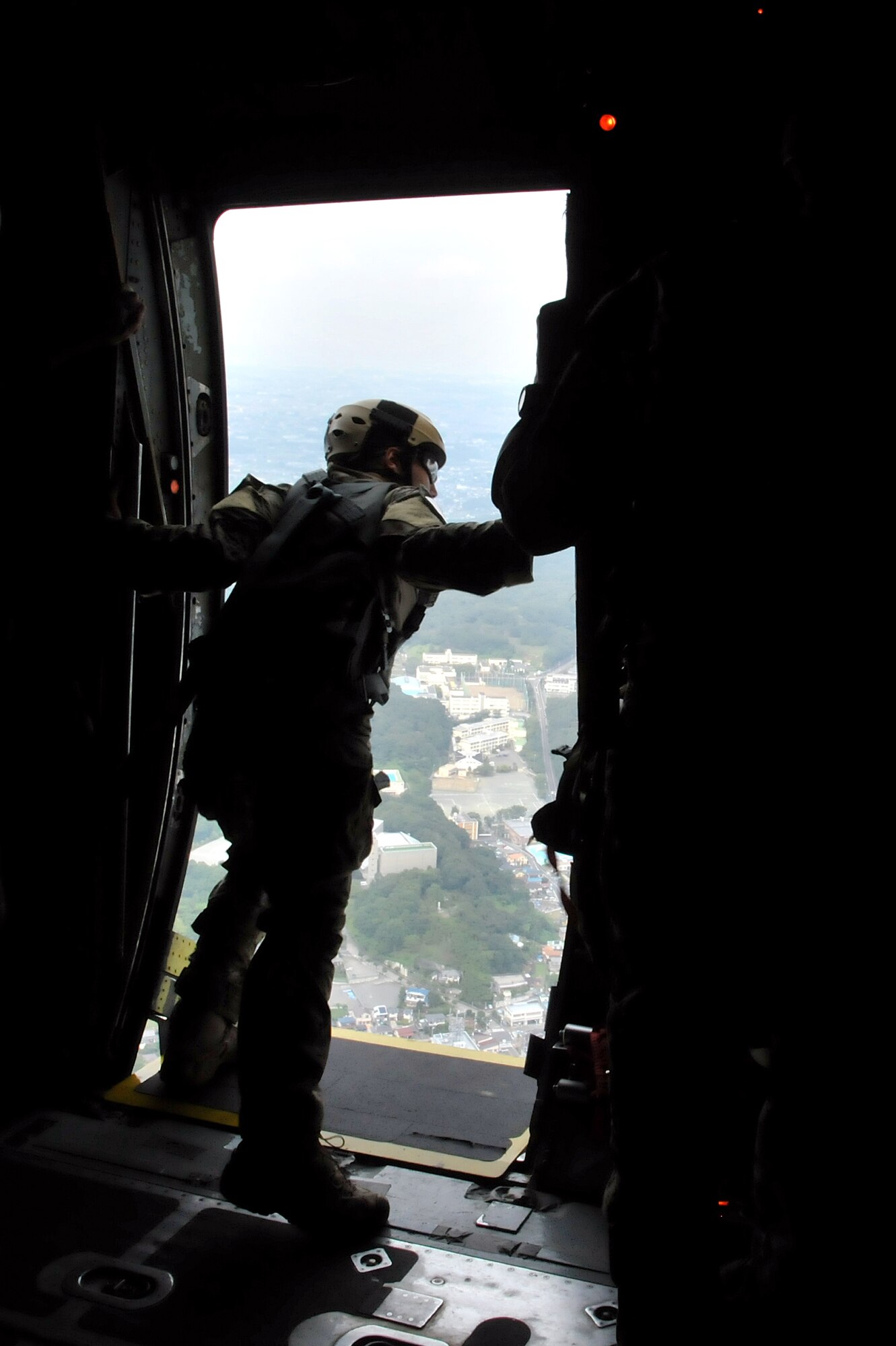 A U.S. Army jumpmaster checks the approaching drop zone from a C-130 Hercules troop door during joint jump training at Yokota Air Base, Japan, Aug. 21, 2013.  The jumpmaster is responsible for ensuring paratroopers exit the aircraft in a timely manner.  (U.S. Air Force photo by Airman 1st Class Soo C. Kim)