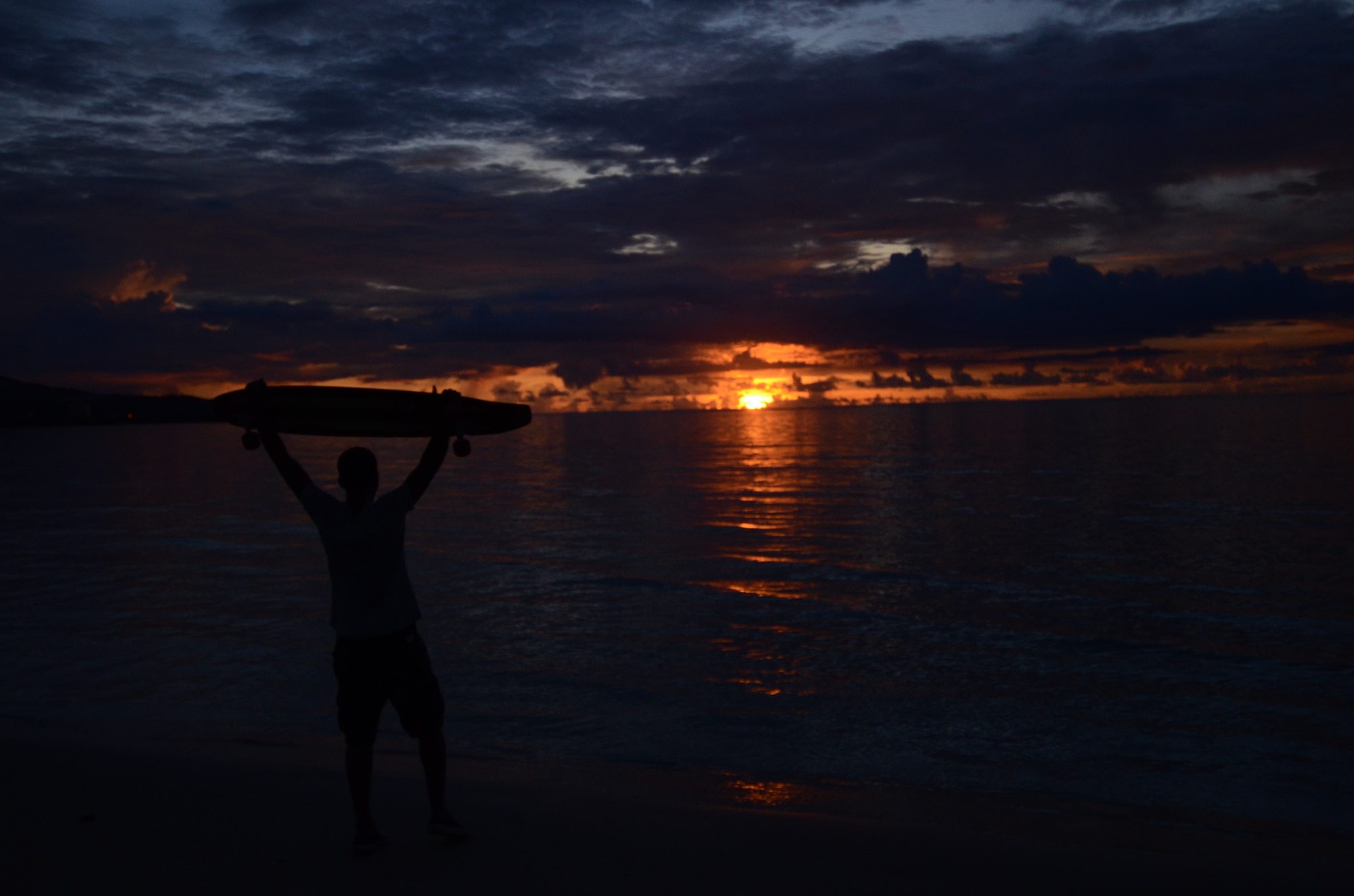 Airman 1st Class Vince Ligon, 36th Communications Squadron cyber system server administrator, watches the sun set by a beach near Andersen Air Force Base, Guam, after finishing long boarding session Aug. 15, 2013. One of the longest distances Ligon has ever traveled at one time on his board was approximately 45 miles from Merrillville, Ind., to Chicago. (U.S. Air Force photo by Airman 1st Class Emily A. Bradley/Released)