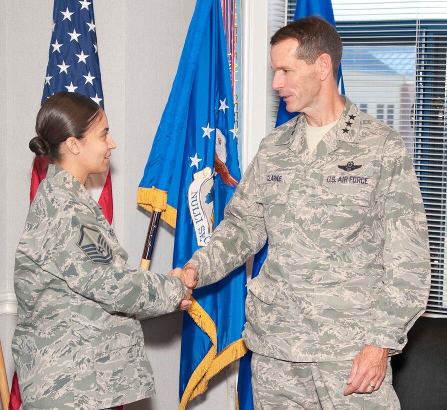 Lt. Gen. Stanley Clarke, director, Air National Guard coins Master Sgt. Nora Castro, 136th Airlift Wing, Texas Air National Guard for serving with distinction at Naval Air Station Fort Worth Joint Reserve Base, Aug. 21, 2013 during his site visit. Lt. Gen. Clarke coined four Airmen from the wing. (Air National Guard photo by Airman Cody Witsaman/released)