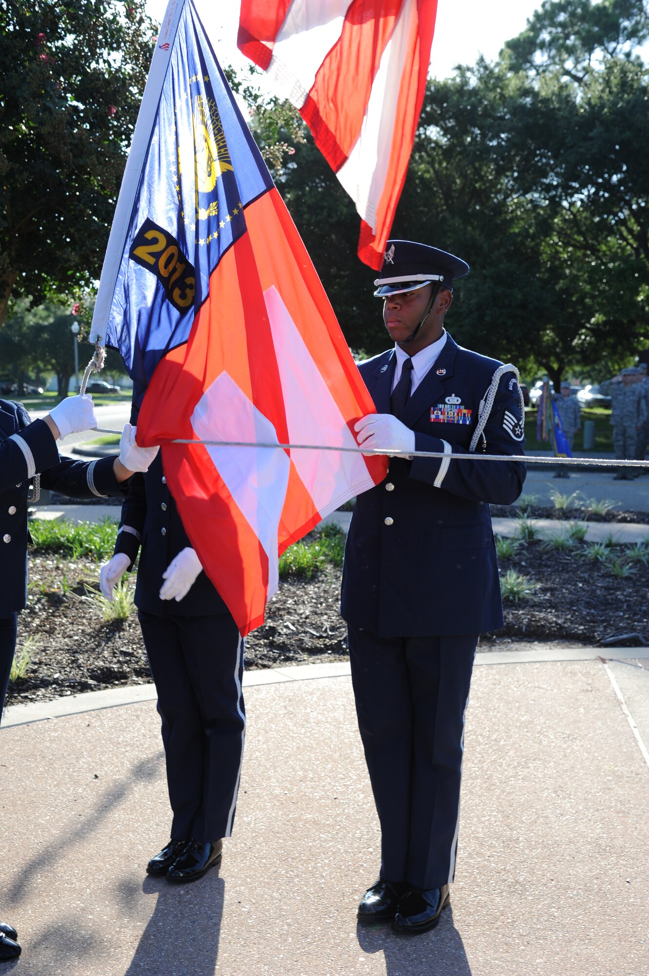 Staff Sgt. Vernon Peoples, Keesler Honor Guard, holds the Commander-in-Chief’s Installation Excellence award flag as it is raised below the American flag in front of the 81st Training Wing headquarters building Aug. 22, 2013, at Keesler Air Force Base, Miss.  Keesler was presented the award in April, 2013. (U.S. Air Force photo by Kemberly Groue)