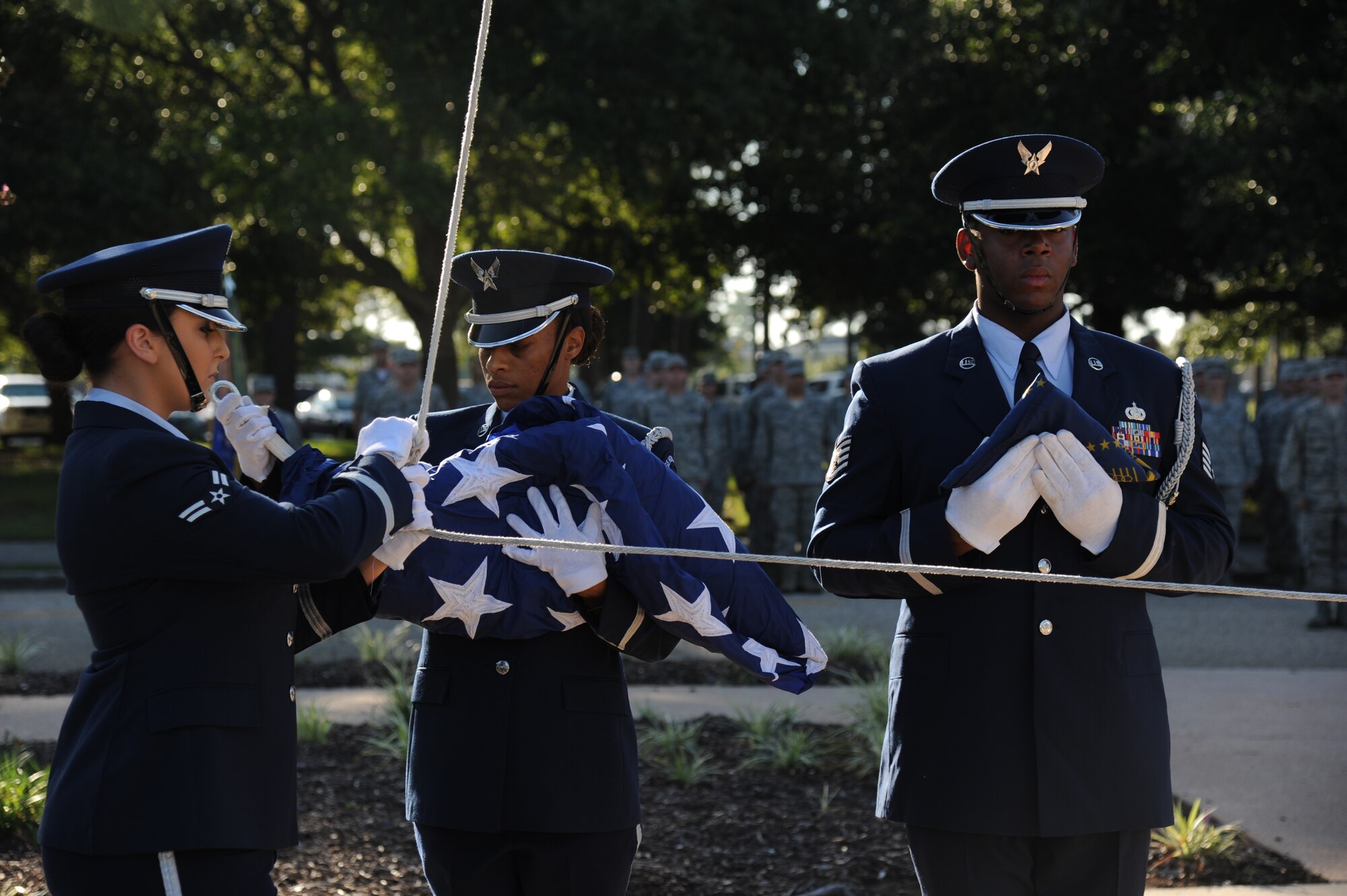 Airman 1st Class Carly Cervantes, Tech. Sgt. Kimberly Williams-Mason and Staff Sgt. Vernon Peoples, Keesler Honor Guard, prepare to raise the American flag and the Commander-in-Chief’s Installation Excellence award flag in front of the 81st Training Wing headquarters building Aug. 22, 2013, at Keesler Air Force Base, Miss.  Keesler was presented the award in April, 2013. (U.S. Air Force photo by Kemberly Groue)