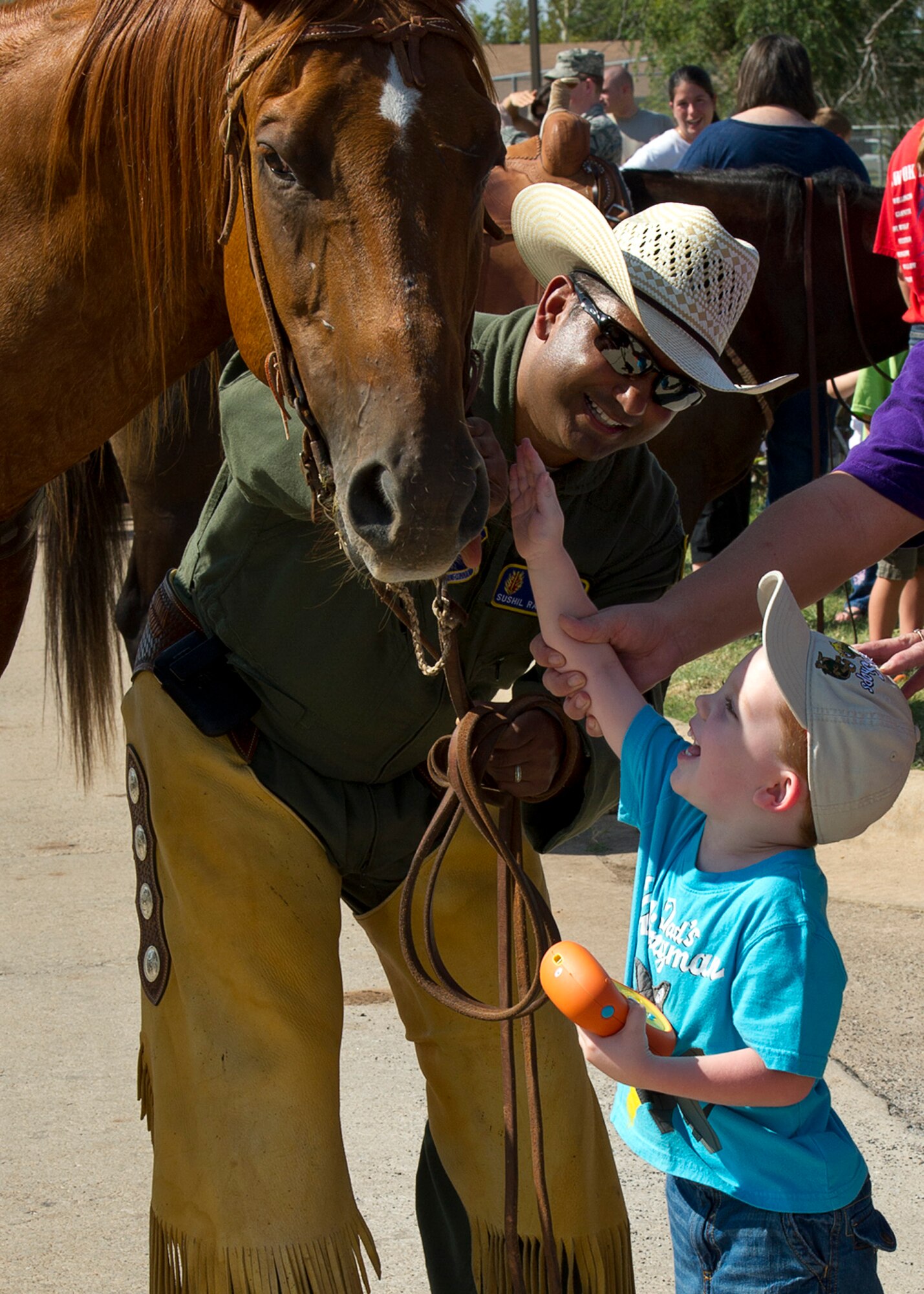 ALTUS AIR FORCE BASE, Okla. -- Col. Sushil Ramrakha, 97th Air Mobility Wing vice commander, helps Byron Leistikow pet a horse during the annual Cattle Drive on base, Aug 22. More than 100 volunteers rode horses during the cattle drive, which carried on the tradition started Aug. 26, 1999 when 15 riders drove a herd of about 30 longhorn cattle through the streets of Altus AFB to kick off the Great Plains Stampede Rodeo. (U.S. Air Force photo by Senior Airman Kenneth W. Norman / Released)