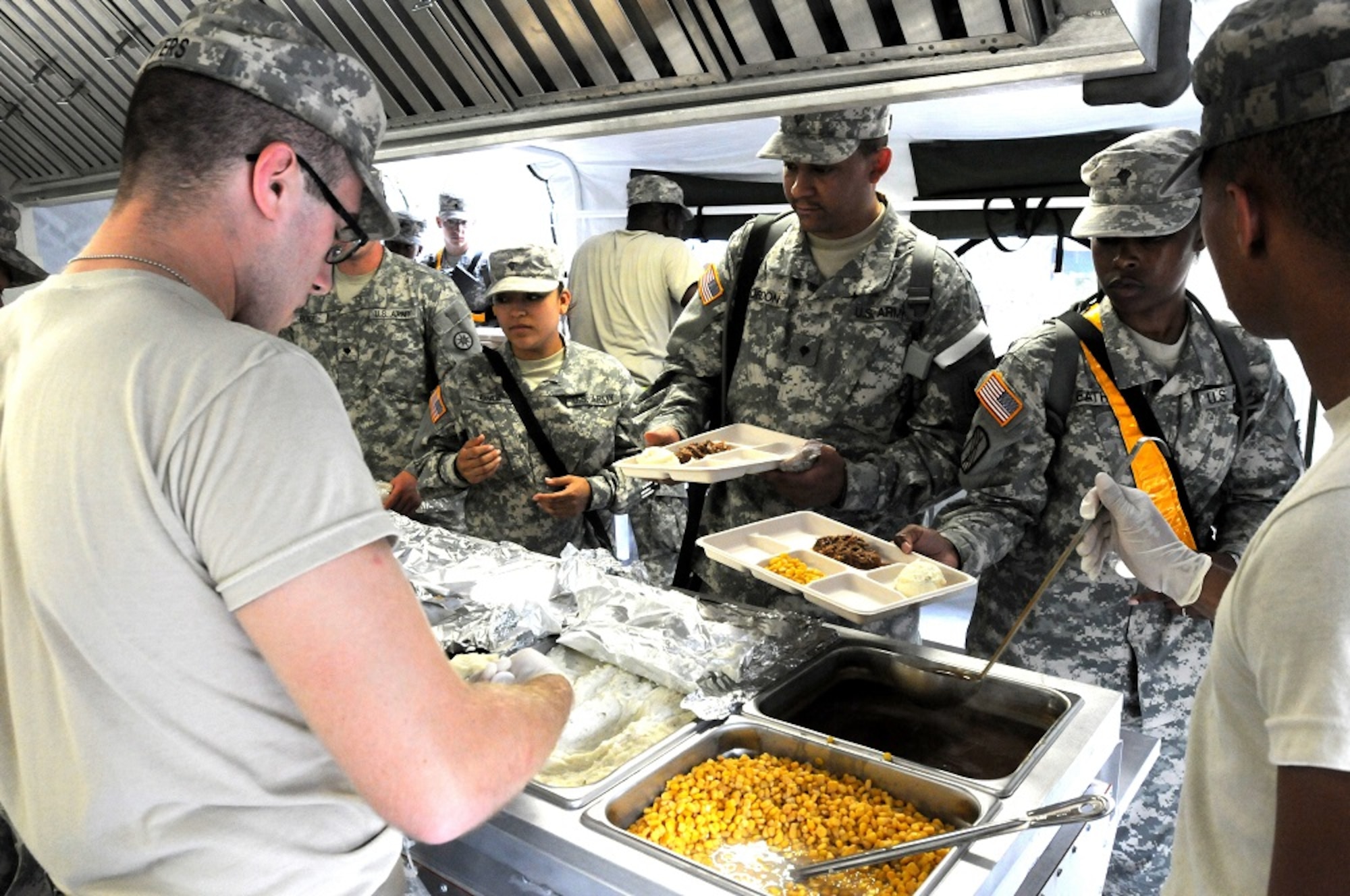 Food service specialists serve chow to soldiers in a Containerized Mobile Kitchen Trailer during Operation Sustainment Warrior, Joint Base McGuire-Dix-Lakehurst, N.J., Aug. 10 2013. Food service specialists are primarily responsible for preparing and serving food in field or in garrison. (U.S. Army photo by Spc. Thomas Crough/Released)