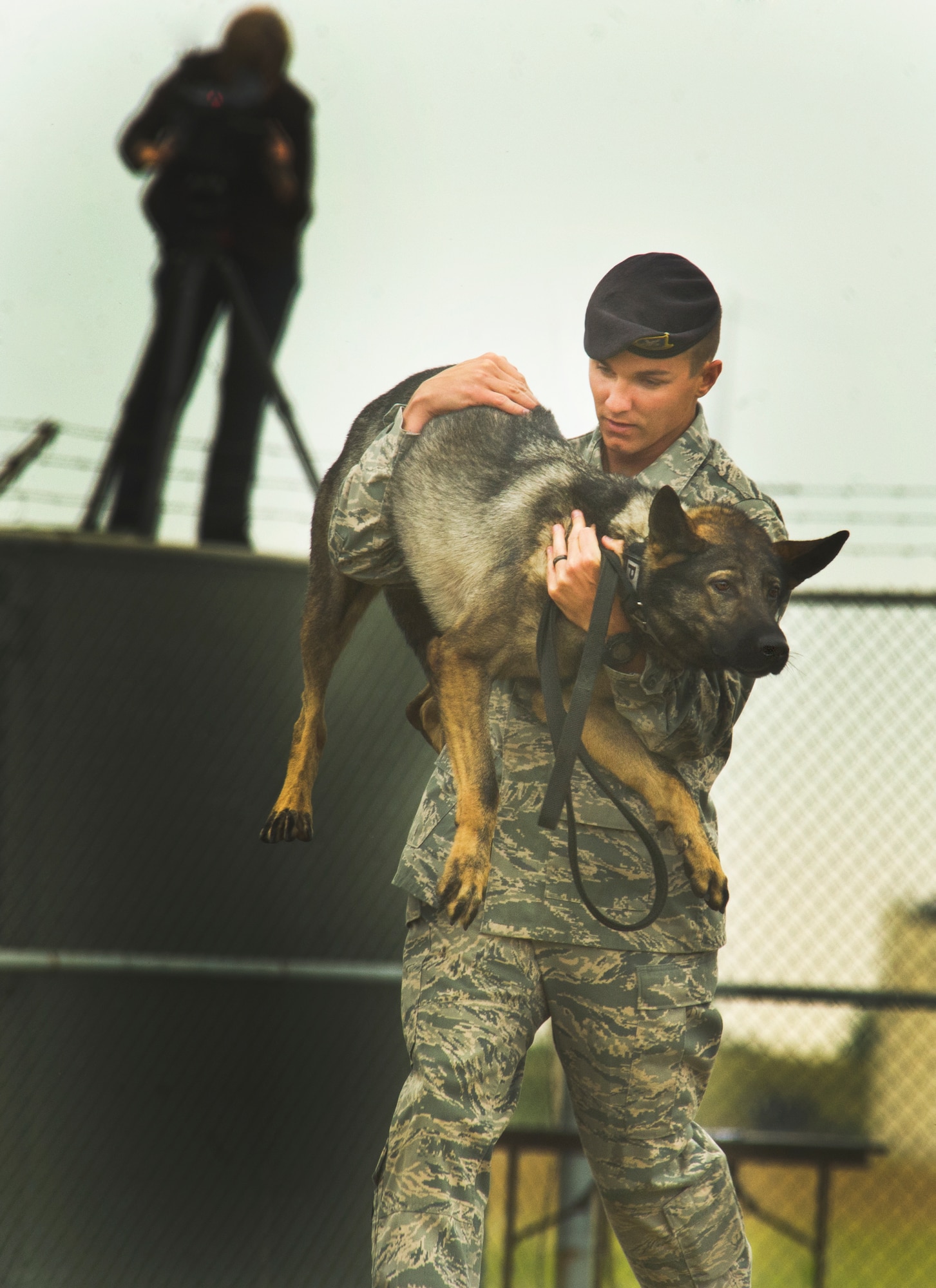 Staff Sgt. Christopher Averill, 5th Security Forces Squadron military working  dog handler, carries 5-year-old German Sheppard Kety during the 2013 North Dakota Peace Officer Association K-9 Police Trials at Minot Air Force Base, N.D., Aug. 14, 2013. The competition brought police, military and security K-9 teams from around the state together in a friendly yet competitive environment. (U.S. Air Force photo/Senior Airman Brittany Y. Auld)