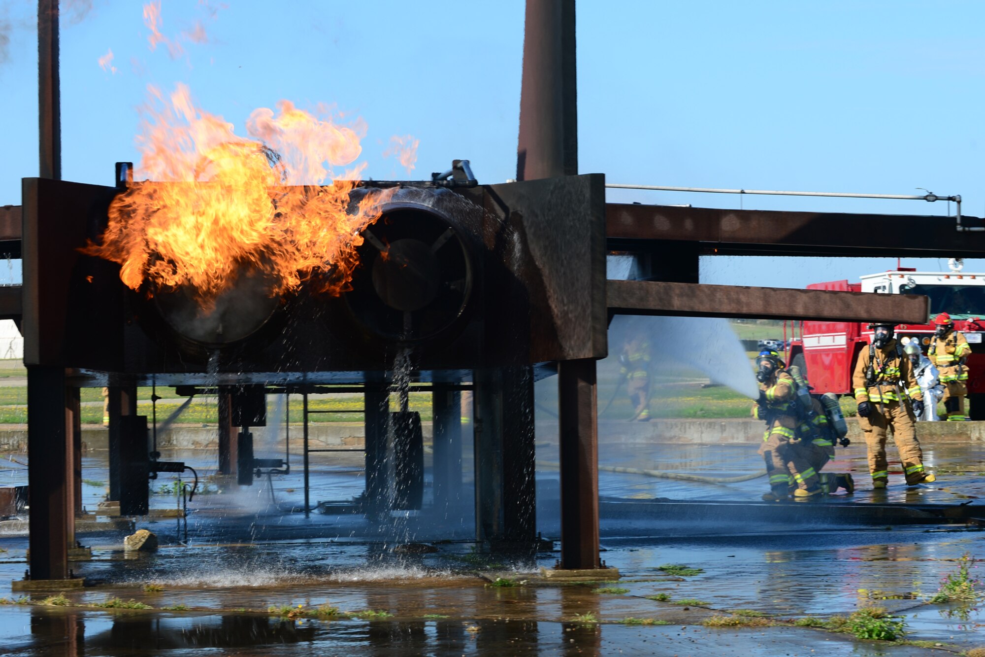 Airmen from the 48th Civil Engineer Squadron Fire Department spray a mock-up F-15 with a fire hose during live-fire training at the burn pit on Royal Air Force Lakenheath, England, Aug. 20, 2013. Live-fire training is mandatory for firefighters to complete twice a year. The training ensures firefighters are able to perform required core tasks in the event of an aircraft fire. (U.S. Air Force photo by Airman 1st Class Dana J. Butler/Released)