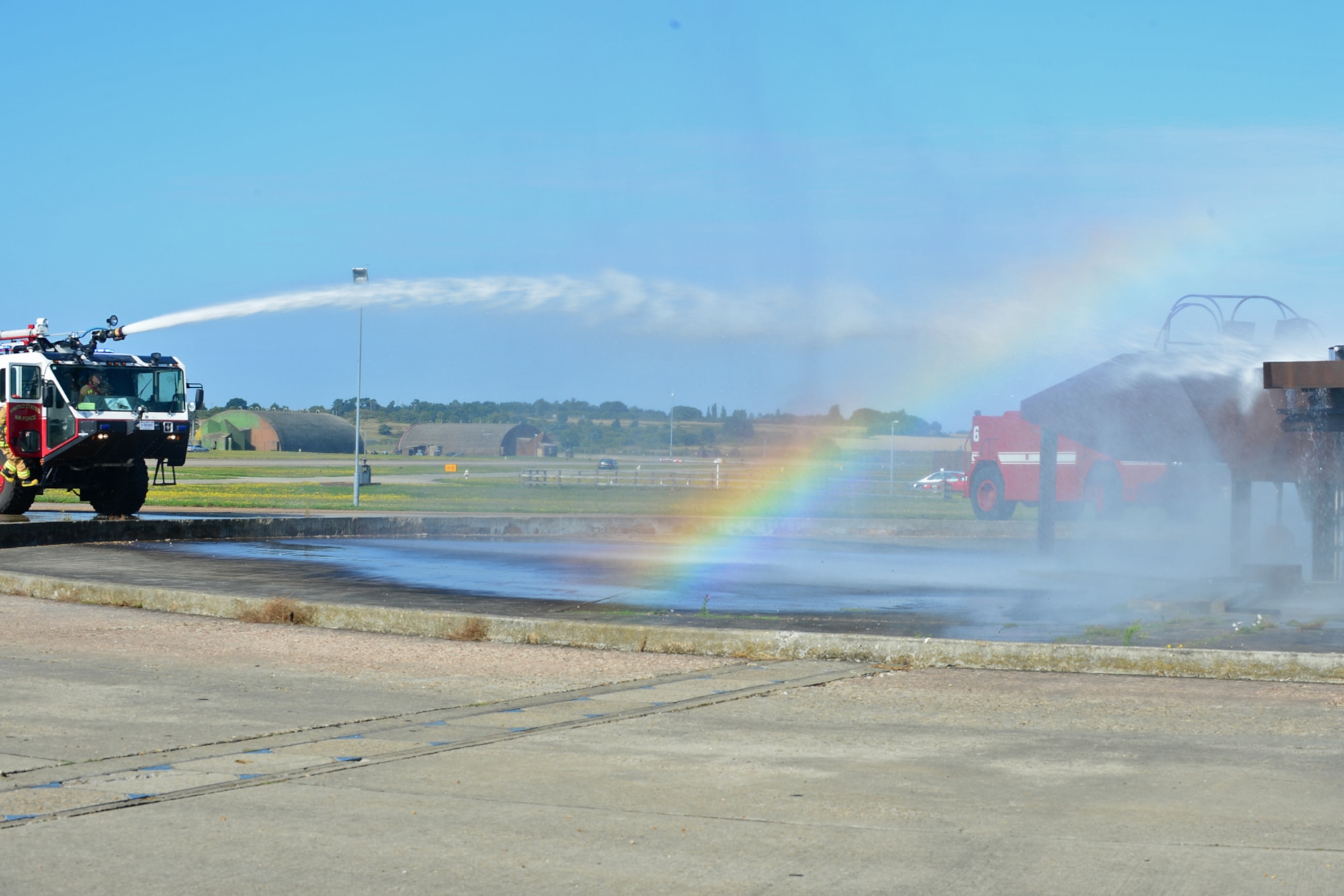 Airmen from the 48th Civil Engineer Squadron Fire Department spray a mock-up F-15 with a fire truck hose during live-fire training at the burn pit on Royal Air Force Lakenheath, England, Aug. 20, 2013. Live-fire training is mandatory for firefighters to complete twice a year. The training ensures firefighters are able to perform required core tasks in the event of an aircraft fire. (U.S. Air Force photo by Airman 1st Class Dana J. Butler/Released)