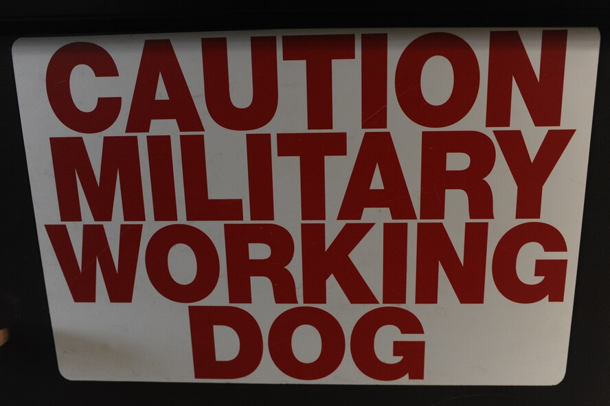 A military working dog caution sign hangs on a fence at the Minot Air Force Base, N.D. kennels. The first cooperative, 2013 North Dakota Peace Officer Association K-9 Police Trials competition, which included military members and local law enforcement officials, took place at Minot AFB, Aug. 14. (U.S. Air Force photo/Airman 1st Class Stephanie Sauberan)