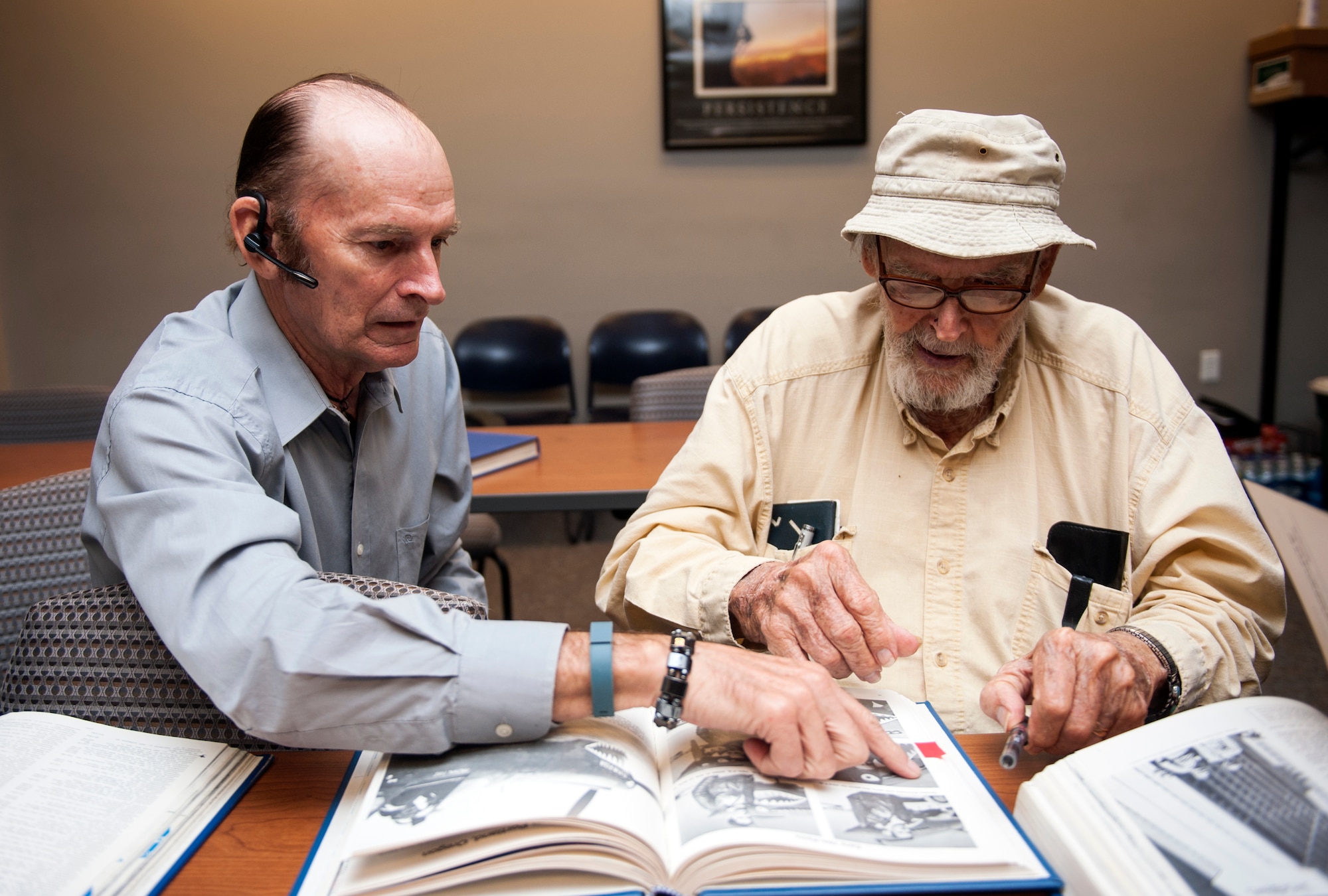 Retired Lt. Col. Harold Stuart, a former 76th Fighter Squadron P-40 Warhawk pilot, and his coworker, Dex Dexter, look at a photo of Stuart from his time in China, while visiting Moody Air Force Base, Ga., July 22, 2013. Dexter and Stuart are both volunteers with the Citizen Observer Program in Orlando, Fla. (U.S. Air Force photo by Senior Airman Jarrod Grammel/Released)
